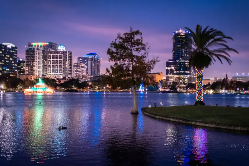 Downtown Orlando skyline at twilight reflected in Lake Eola with palm trees