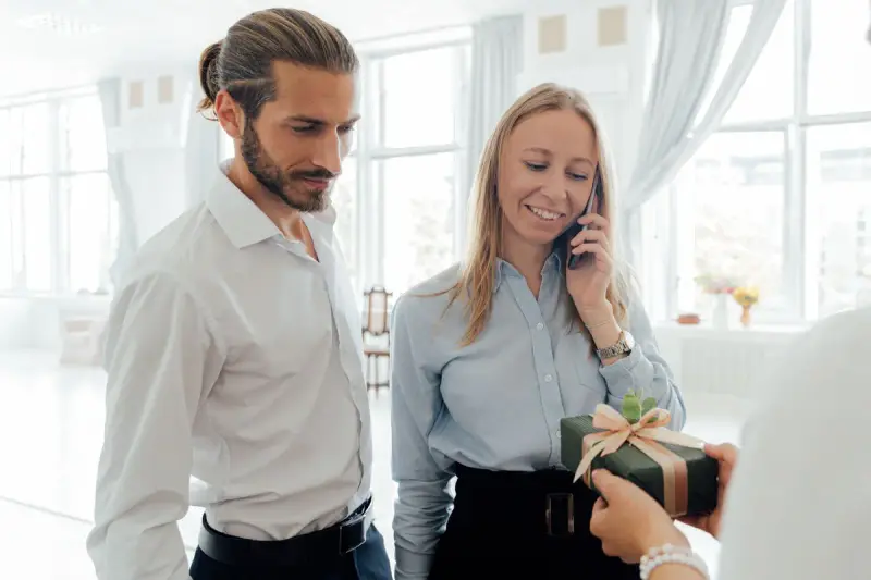 Smiling office colleagues with a wrapped gift box in a bright workspace