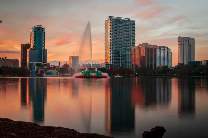 Orlando skyline at sunset with the Lake Eola fountain reflected in calm water