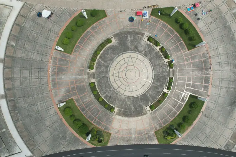 Aerial view of a circular plaza with geometric paving surrounded by trees and lawns