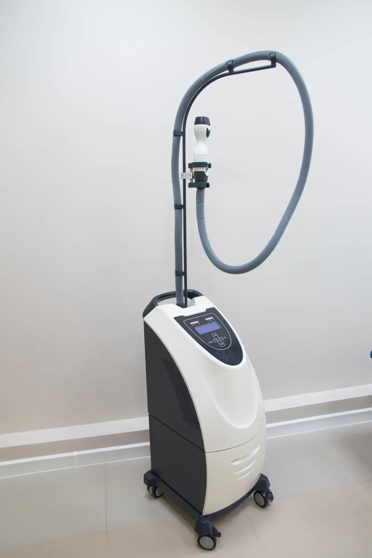 A clinical laser device with its screen and handpiece supports visible