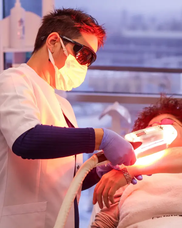 Professional providing a light-based skin treatment with protective eyewear