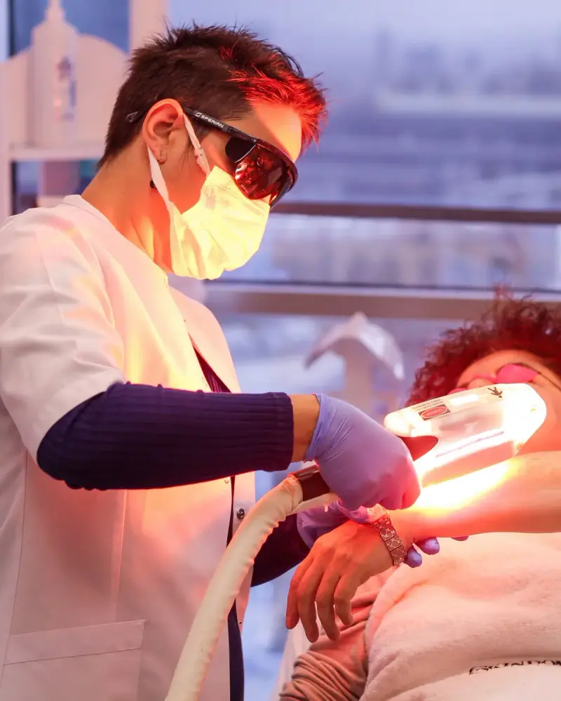 Professional providing a light-based skin treatment with protective eyewear