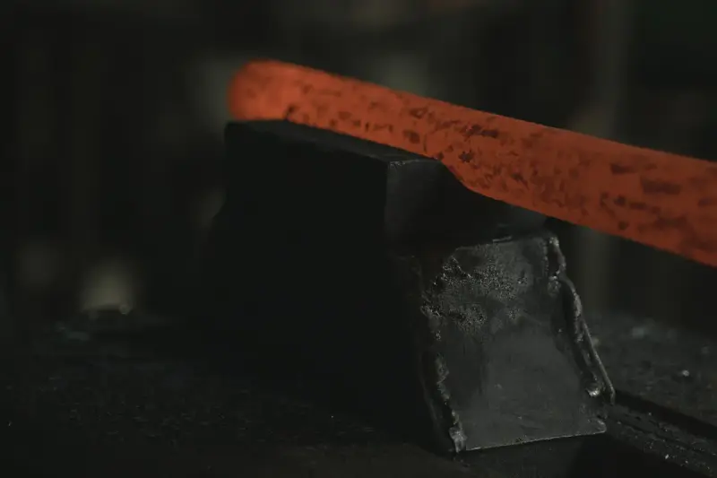 Red-hot steel bar resting across a dark anvil