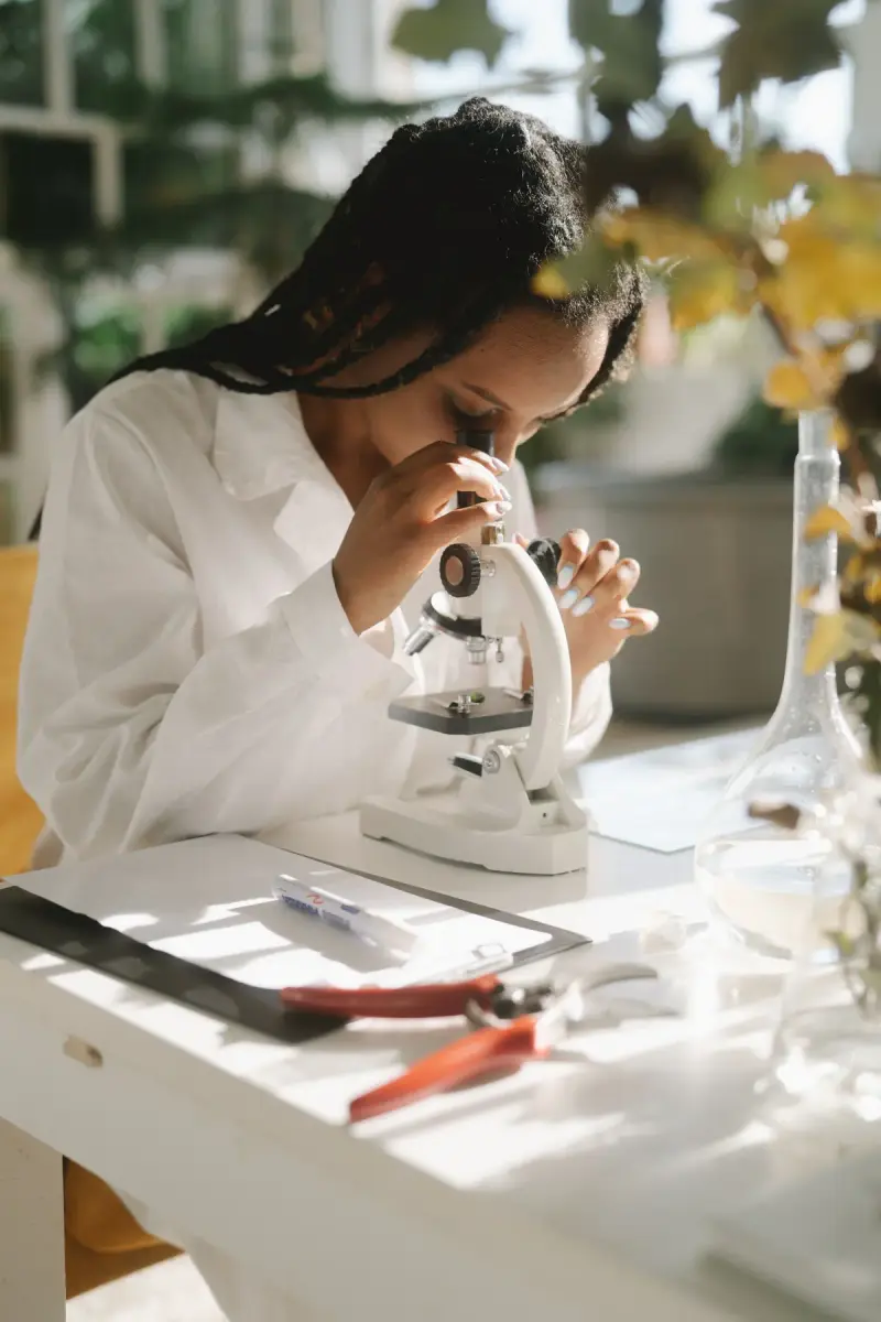 Female scientist in a white lab coat looking through a microscope