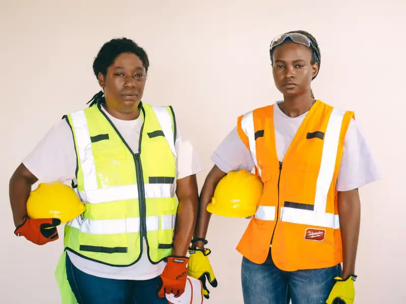 Two women wearing safety vests and helmets at a construction site