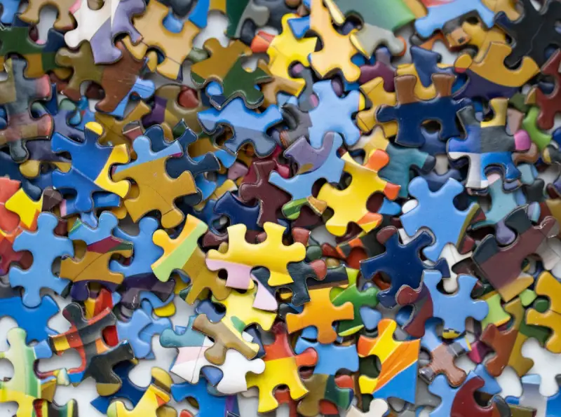 Pile of loose multicolored jigsaw puzzle pieces filling the frame