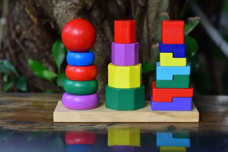 Three colorful wooden stacking and sorting toys on a wooden base