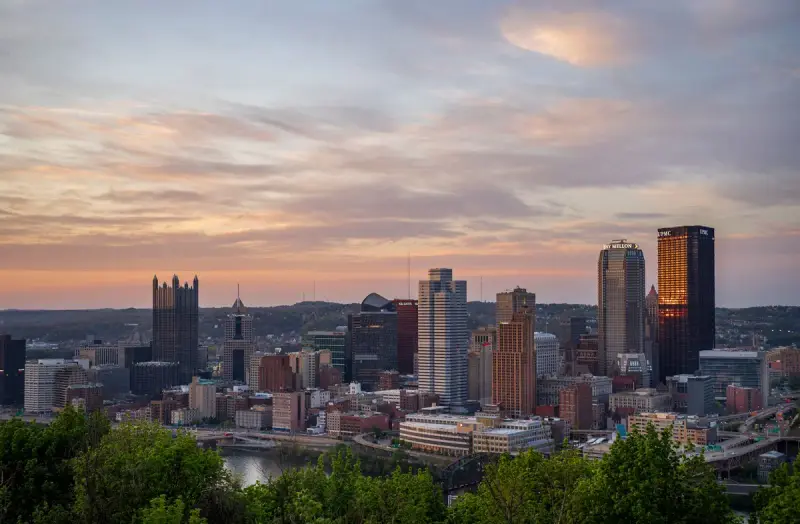 Downtown Pittsburgh skyline and rivers at sunset seen from a hillside