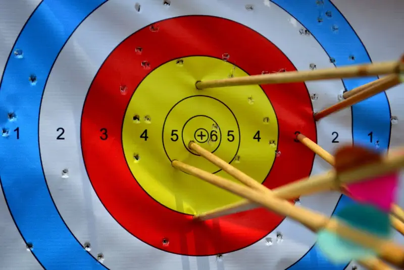 Close view of arrows grouped around the bullseye of a colorful paper target