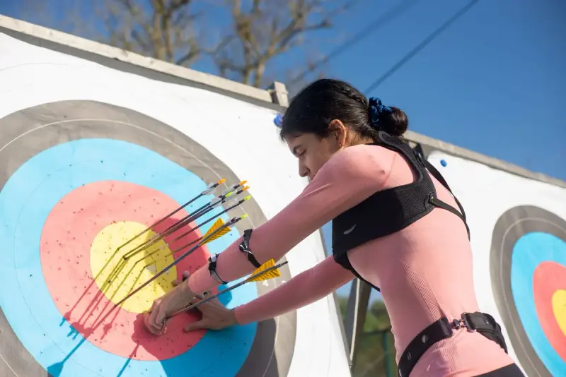 Woman archer pulling arrows from a target face on an outdoor range