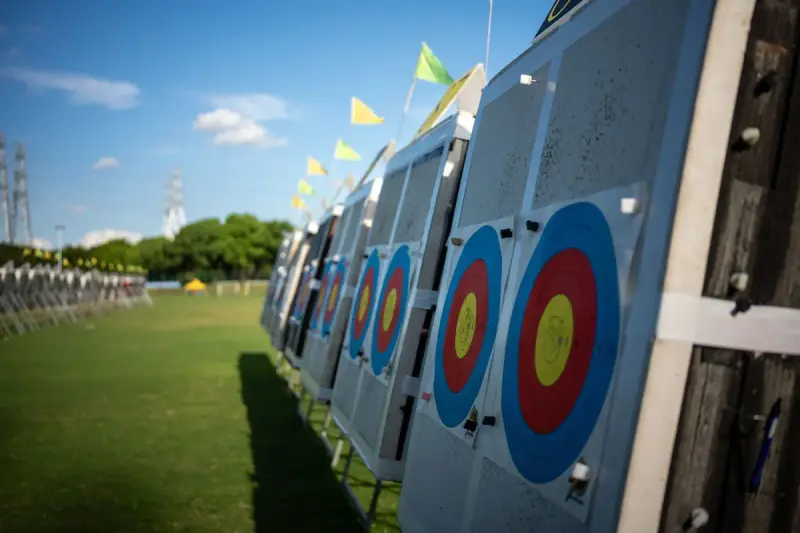 Long line of archery target boards on an outdoor range under a blue sky with flags