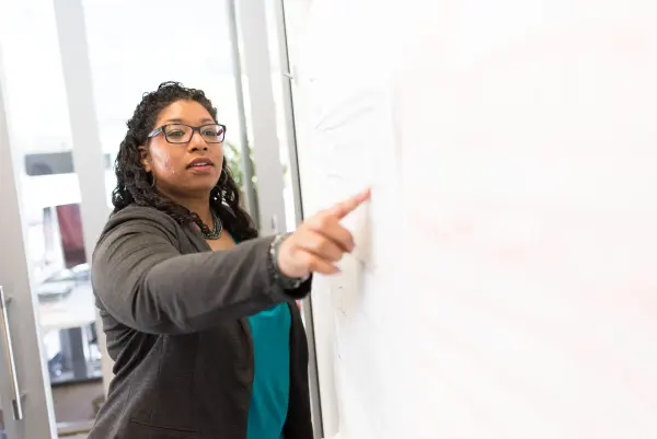 Woman leading a discussion beside an office whiteboard
