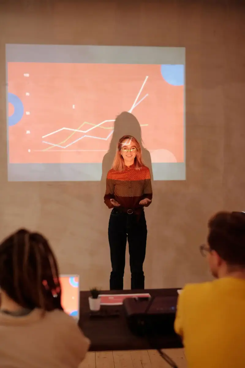 Woman discussing data beside a projected graph