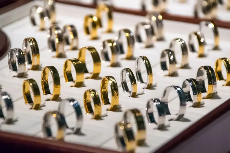 Tray of gold and white gold wedding bands lined up in a jewelry store display