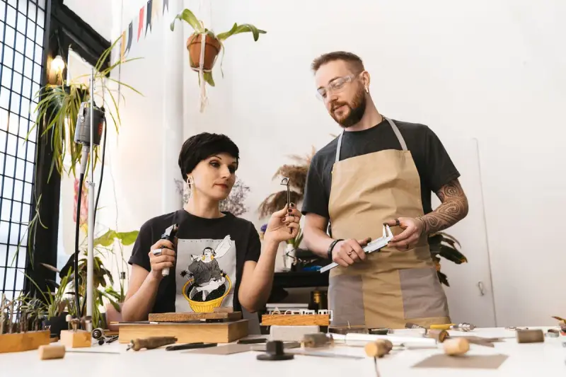 Two artisans working together on jewelry at a workshop bench