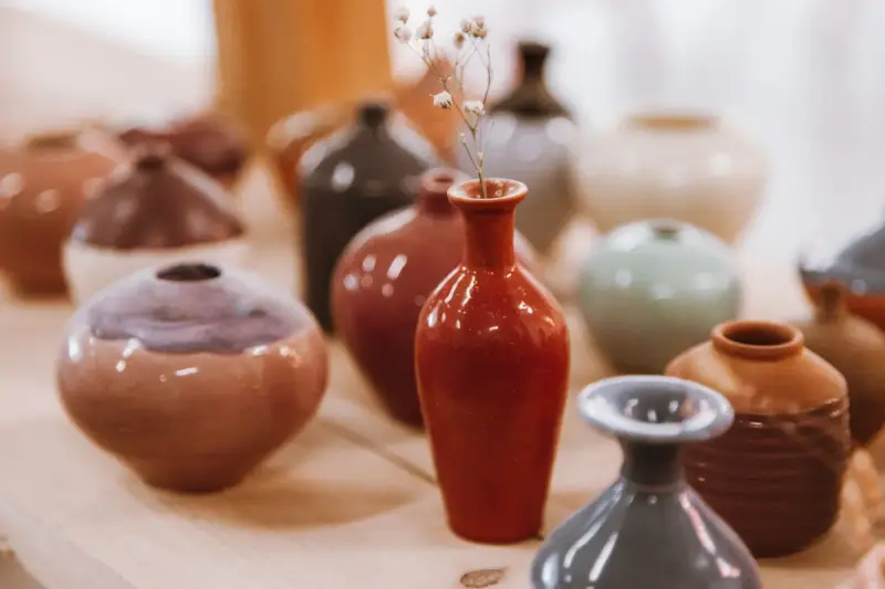 Glazed ceramic vases in terracotta, red, gray and cream tones grouped on a table
