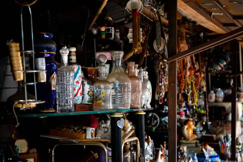 Shelves of vintage glass decanters, bottles and curios in a dimly lit antique store