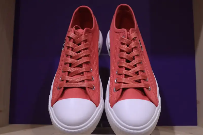 Pair of red canvas sneakers with white rubber toes against a purple backdrop