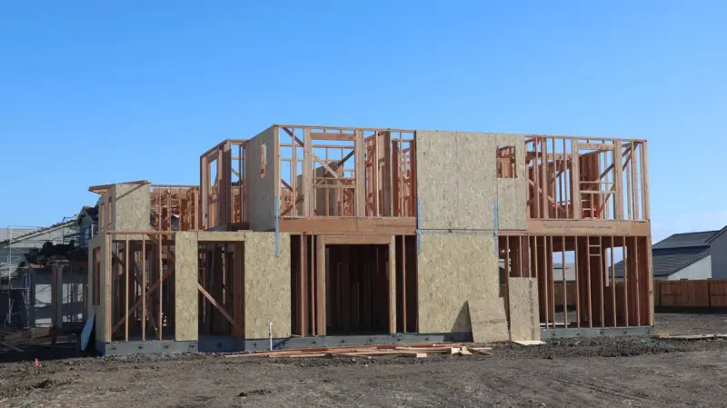 Two-story wood frame house with sheathed walls on a cleared suburban lot