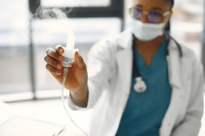 Close-up of a healthcare worker's hands holding a nebulizer mask and tubing