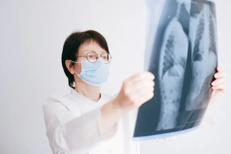 Female doctor in a mask studying a chest X-ray of the lungs