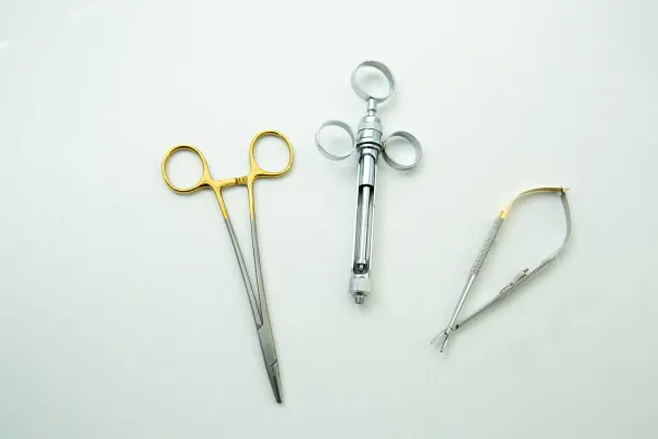 Metal medical instruments arranged on a white surface.