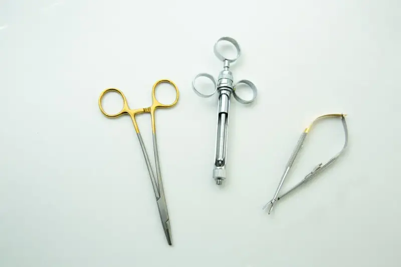 Metal medical instruments arranged on a white surface.