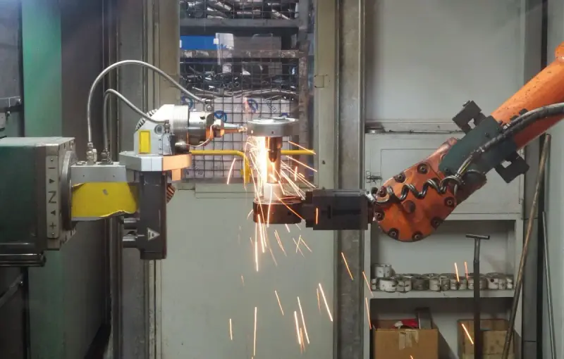 Industrial robot working on a metal component with bright sparks