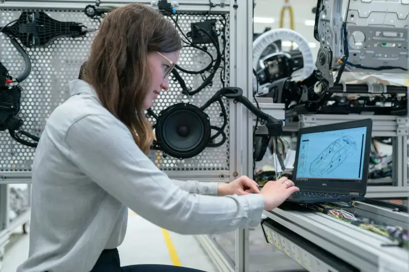 Engineer at a laptop configuring an automated test rig in a workshop