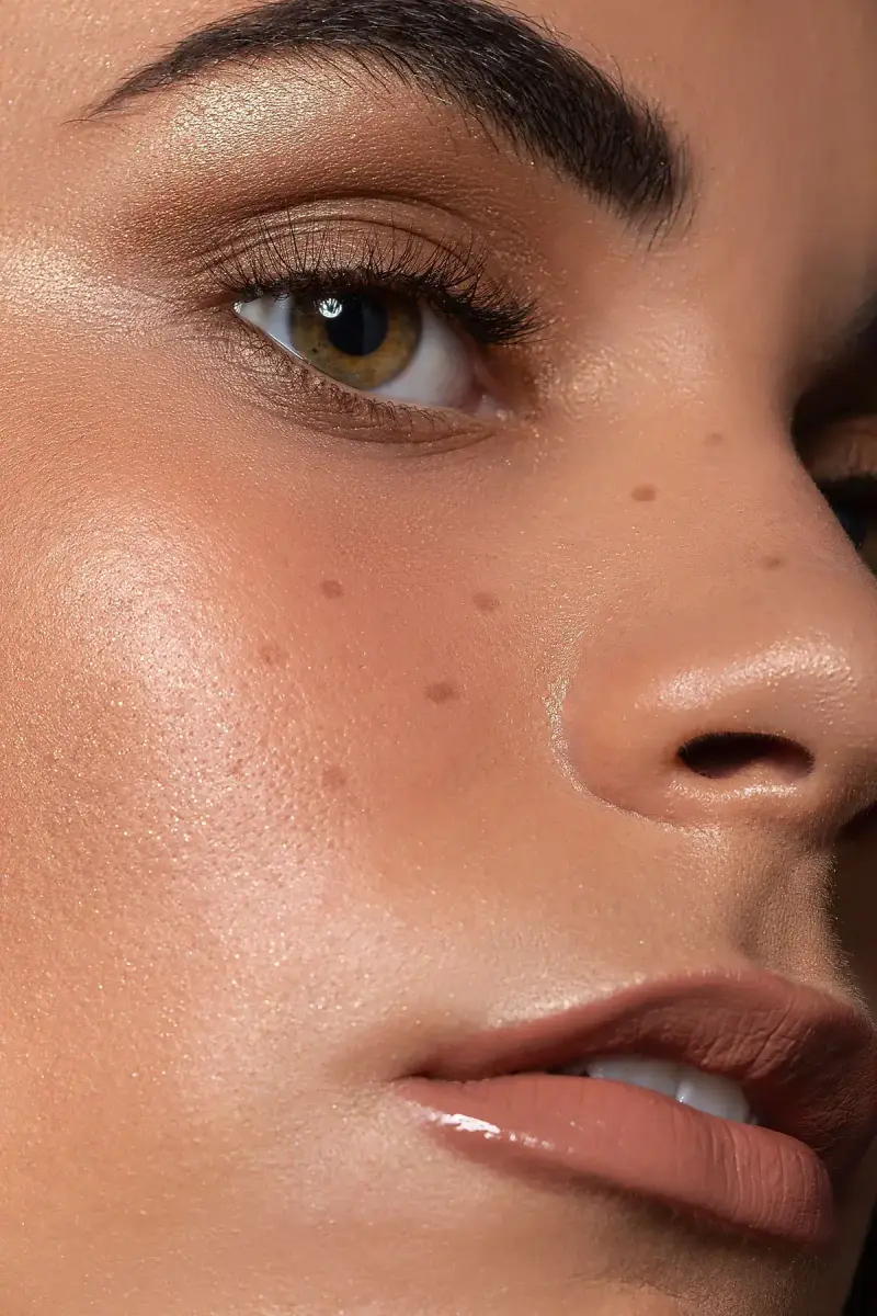 Close-up of glowing dewy skin, freckles and a soft nude lip