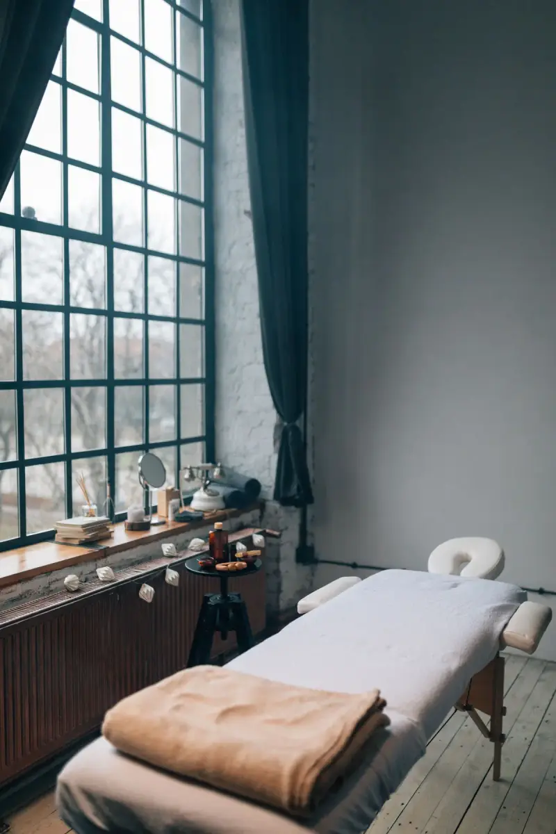 Treatment bed by tall factory windows in a calm spa room