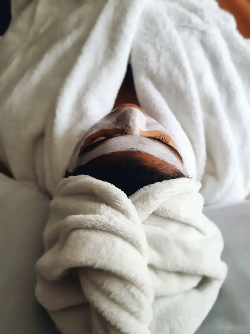 Woman in a white towel wrap with a face mask during a spa treatment