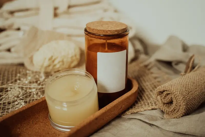 Candles and skincare jars arranged on linen and a wooden tray
