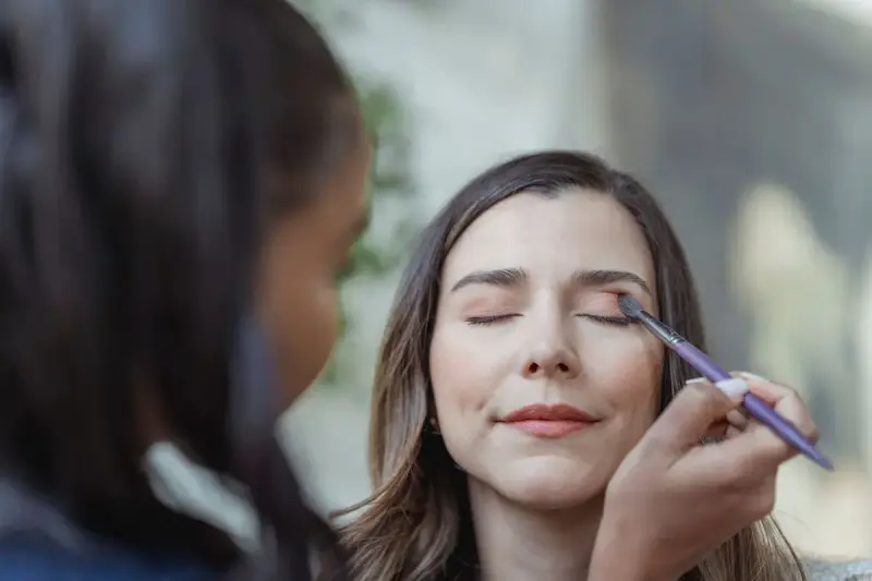 Makeup artist applying eyeshadow to a client's eyelids