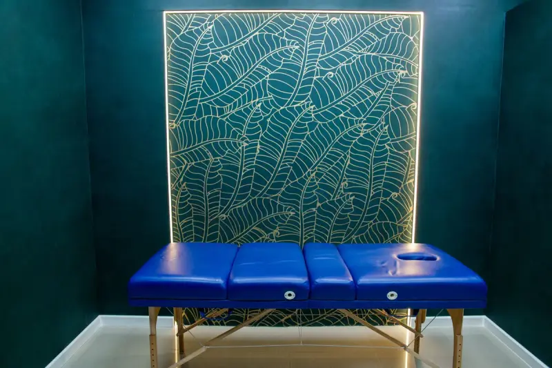 Treatment room with a blue padded bed and a patterned feature wall