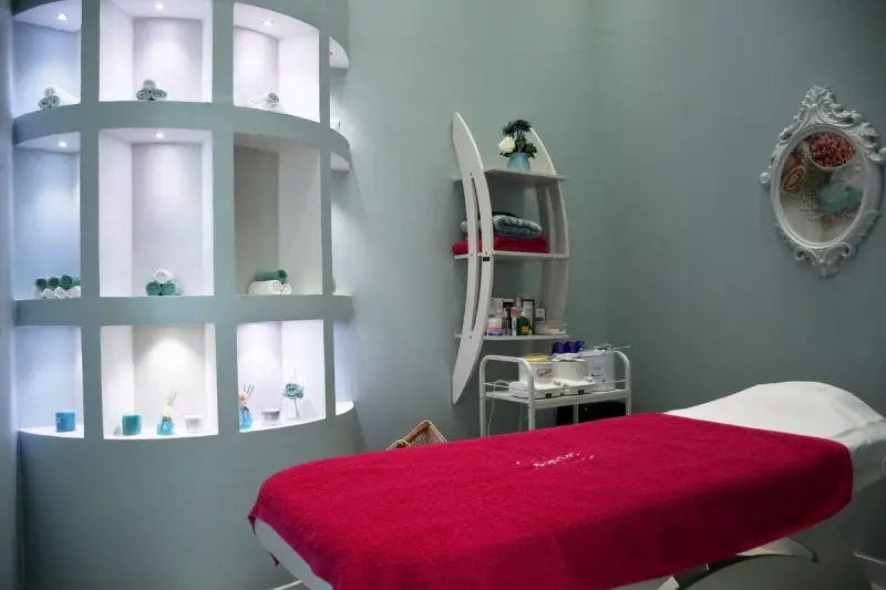 Modern spa treatment room with a bed, ambient lighting and sleek fittings