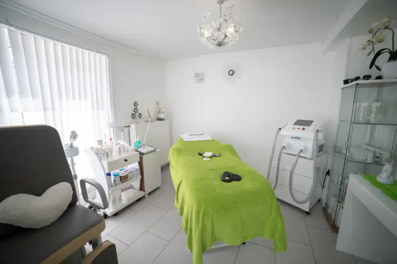 Bright treatment room with a padded bed and skin care equipment