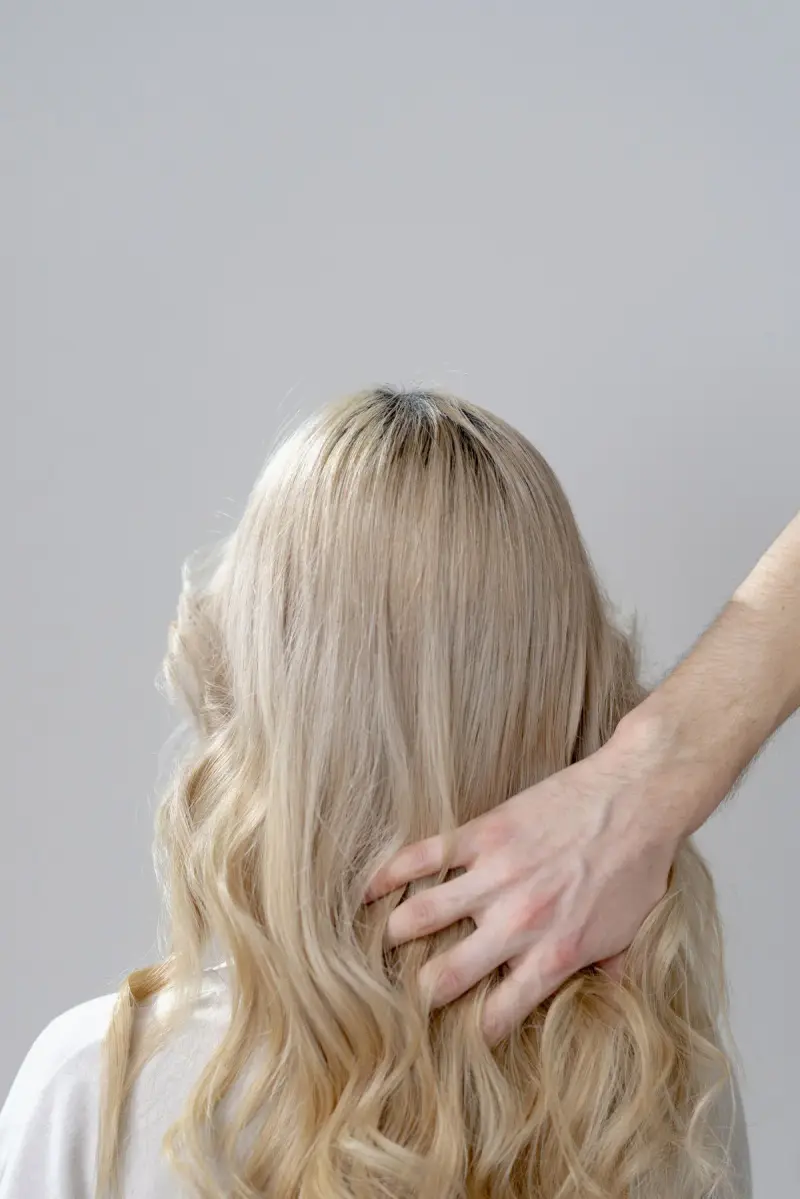 Stylist's hand shaping long blonde curls