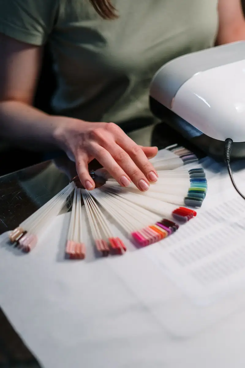 Client choosing a gel polish shade from a sample fan at a nail station
