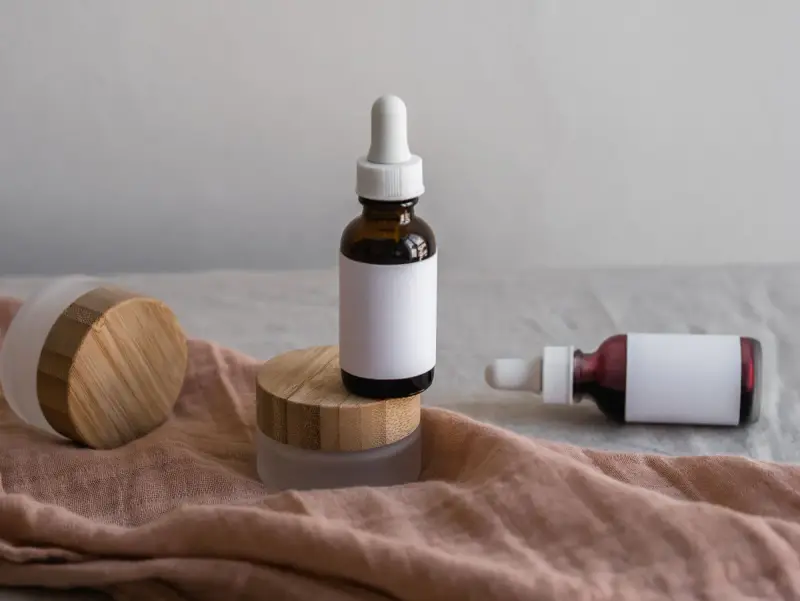 Unlabeled dropper bottles and jars with bamboo lids on a linen cloth
