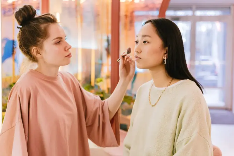 Makeup artist carefully applying makeup to a seated client in a studio