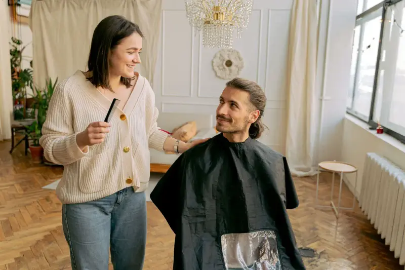 Hairdresser styling a man's hair in a warm, well-lit salon