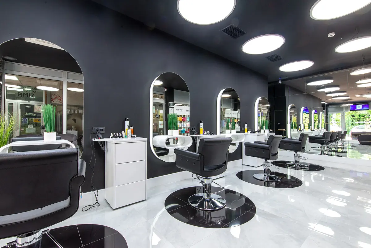 Modern beauty salon with black styling chairs, arched mirrors and round ceiling lights