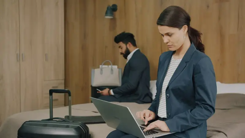 Business travelers working on laptops in a hotel room