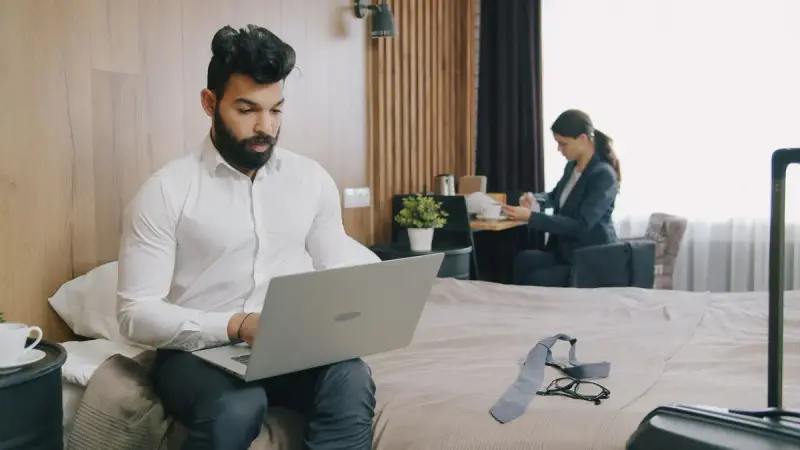 Two professionals working remotely in a hotel room