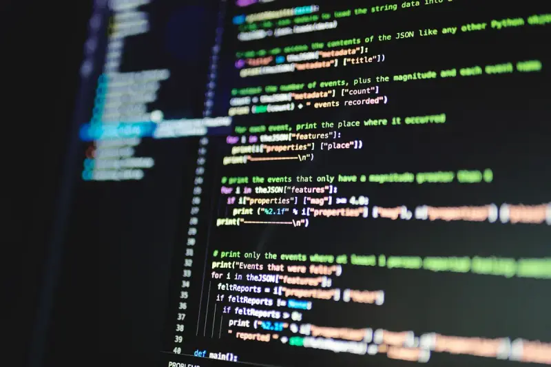Monitor showing colorful lines of programming code in a dark room