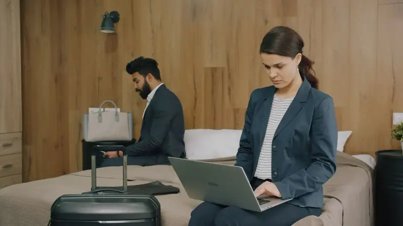 Man and woman working on laptops in a hotel room