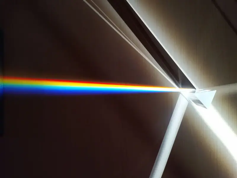 Beam of white light split into a rainbow spectrum by a glass prism
