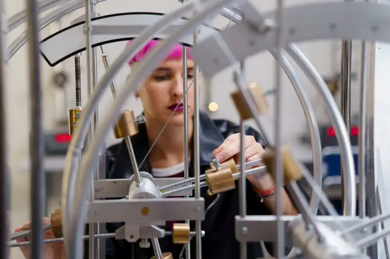 Young woman adjusting a metal physics apparatus in a lab